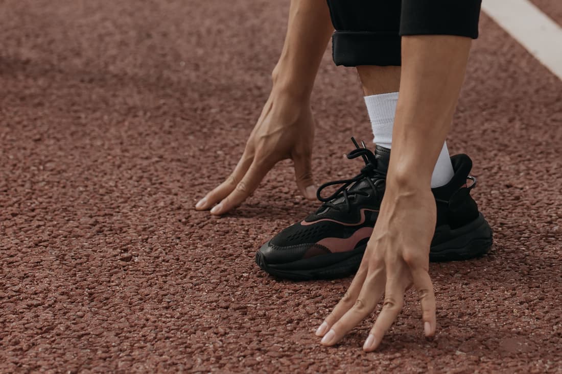 A runner crouched at the start on a red track