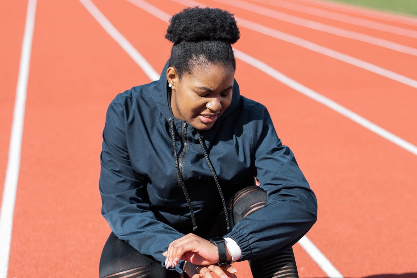 A runner on a track checking a smartwatch